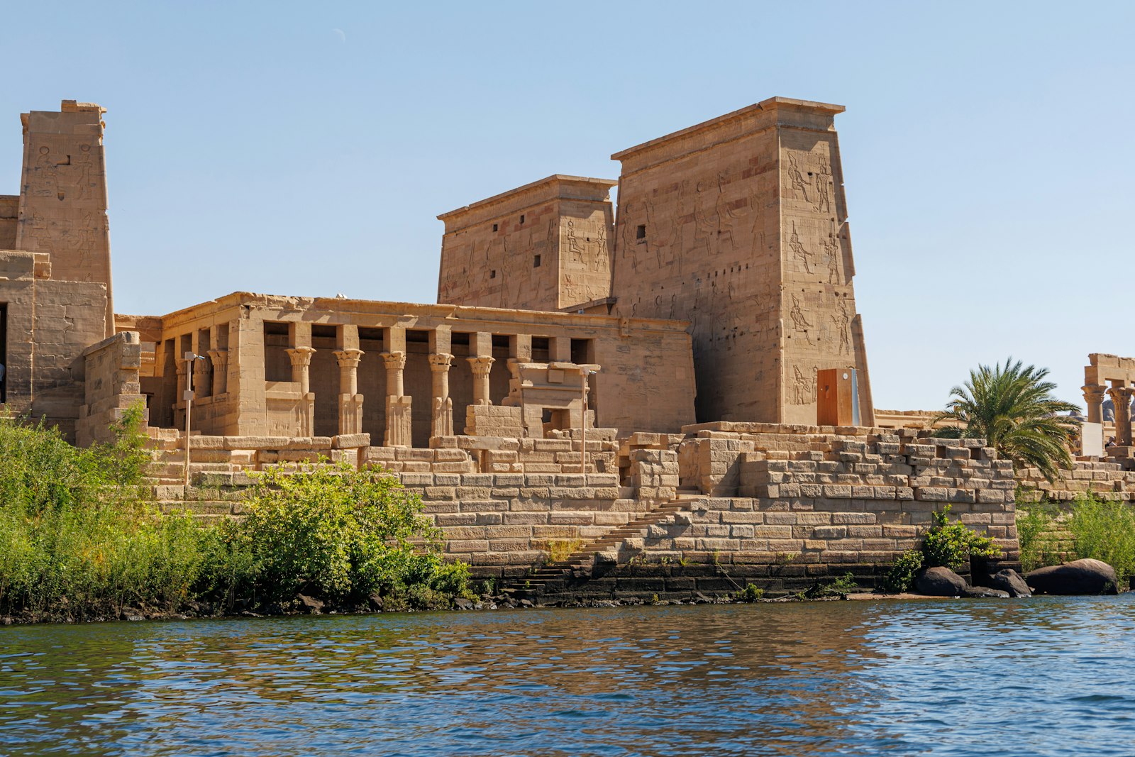 The Temple of Philae rising from the blue waters of the Nile at Aswan under a clear sky